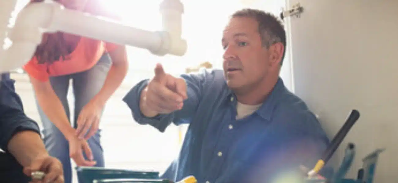 plumber on floor sorting water pipes